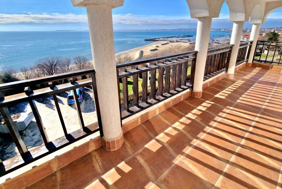 Вид с балкона на пляж и море в Болгарии, солнечное небо, современные архитектурные детали, идеальное место для отдыха и инвестиций.