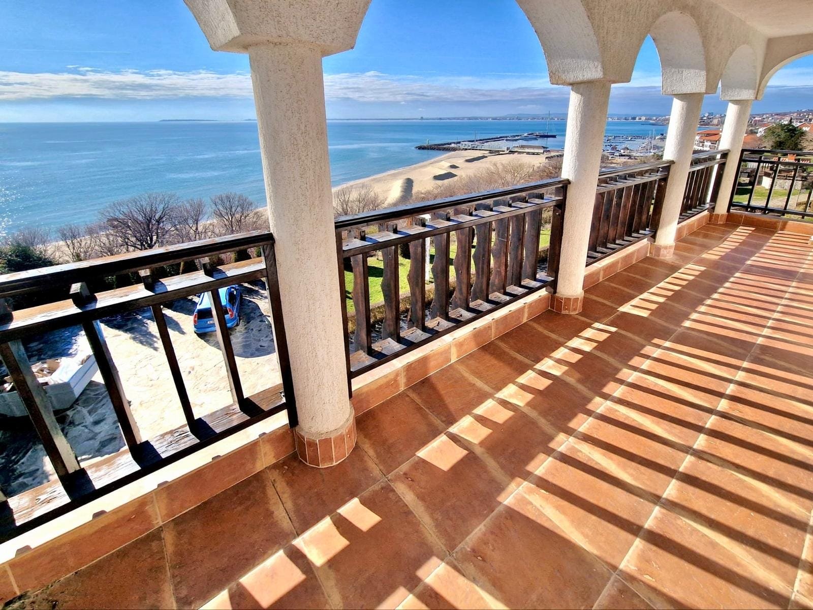 Вид с балкона на пляж и море в Болгарии, солнечное небо, современные архитектурные детали, идеальное место для отдыха и инвестиций.