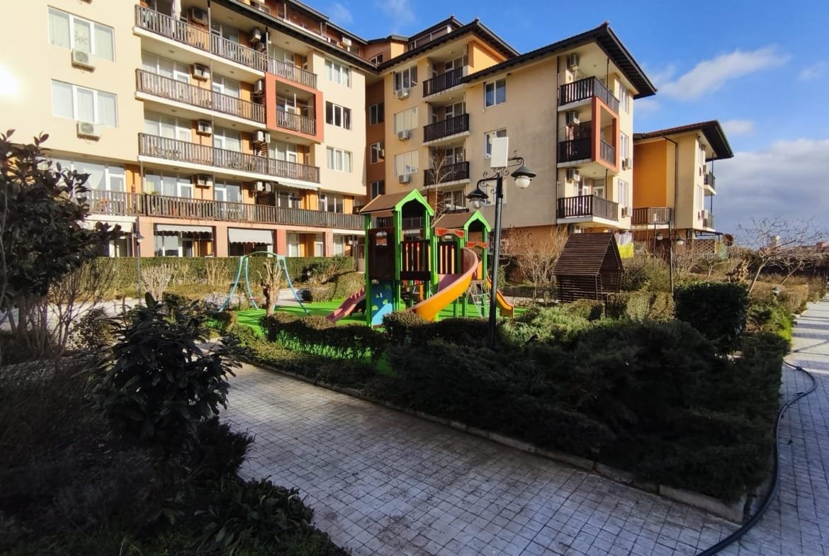 Жилой комплекс в Болгарии с площадкой для детей, зелеными насаждениями и ухоженной территорией для комфортного проживания.