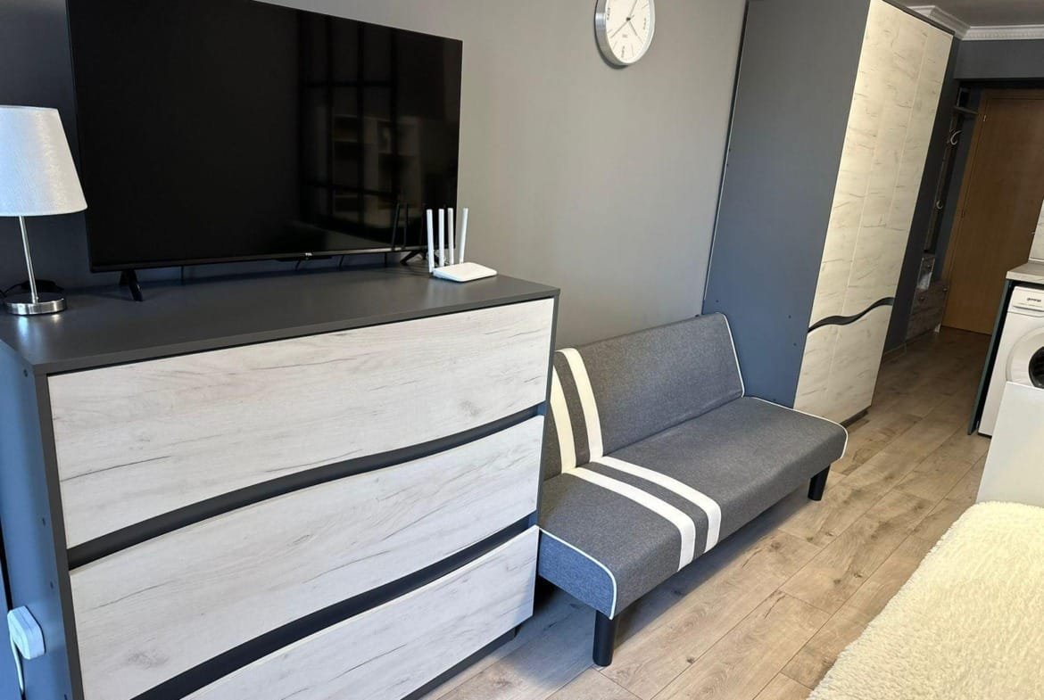 Современный интерьер квартиры в Болгарии с телевизором, диваном и шкафом, создающий уютное пространство для жизни или аренды.