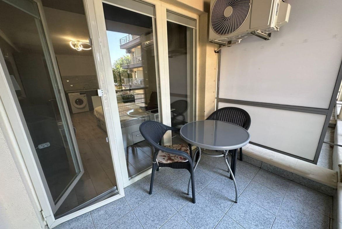 Современный балкон с круглыми столом и стульями, рядом кондиционер, светлое пространство, идеальное для отдыха в Болгарии.