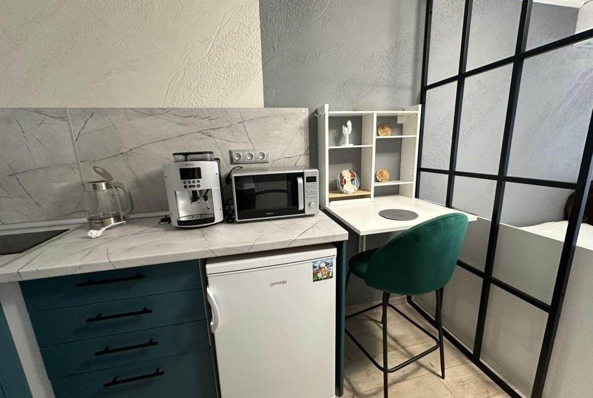 Современная кухня с техникой, столом для работы и зелёным стулом, идеальна для комфортного проживания в Болгарии.