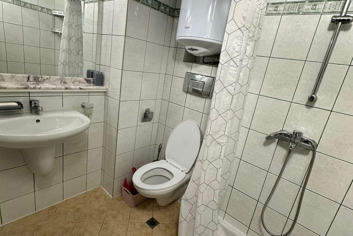 Современно оформленная ванная комната с душевой кабиной, умывальником и унитазом в недвижимости в Болгарии.