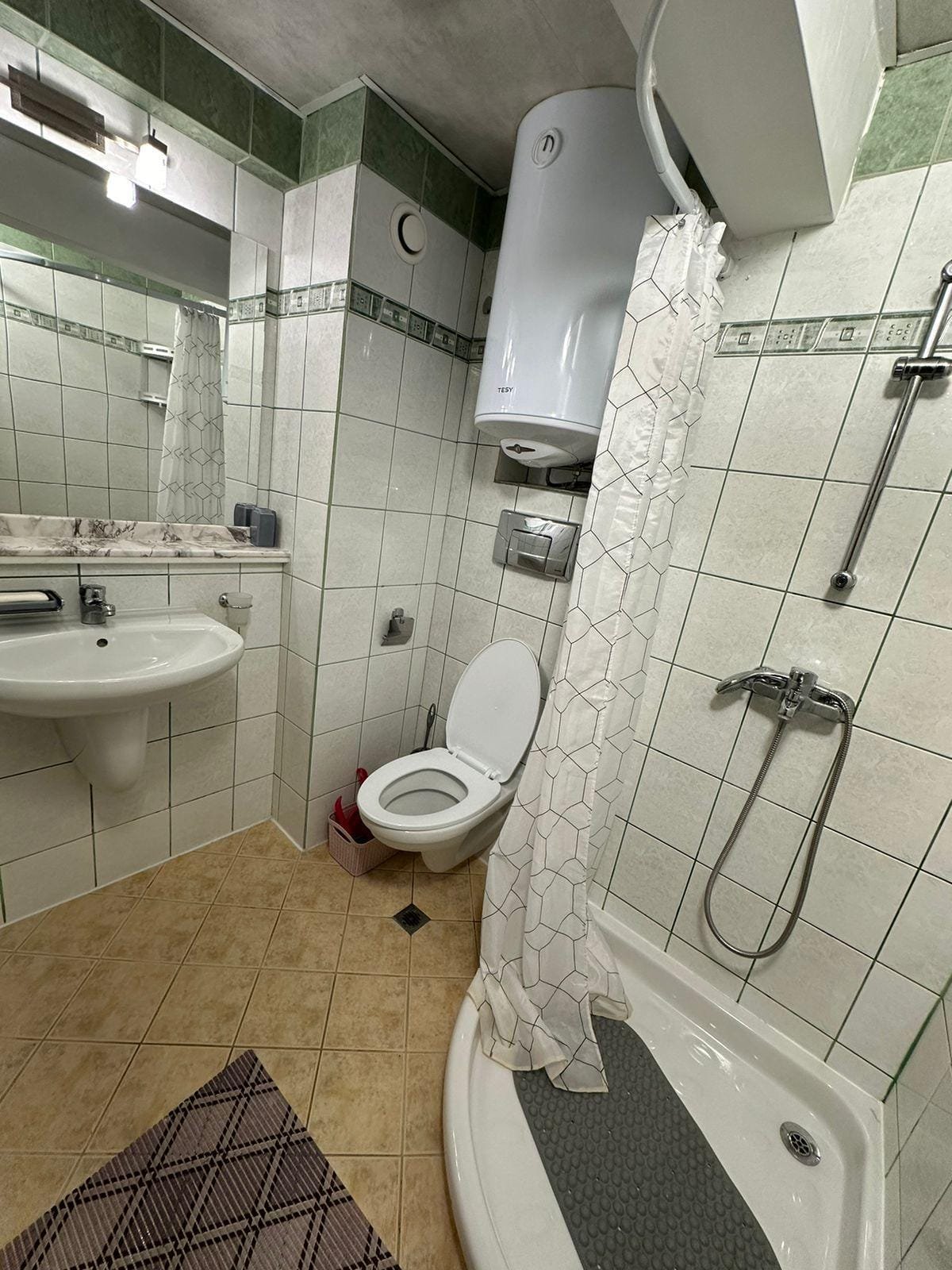 Современно оформленная ванная комната с душевой кабиной, умывальником и унитазом в недвижимости в Болгарии.