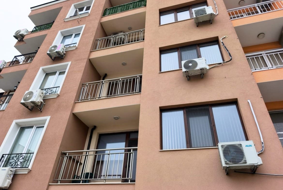 Многоквартирный дом в Болгарии с балконами и кондиционерами, идеальный для покупки или аренды недвижимости у моря.