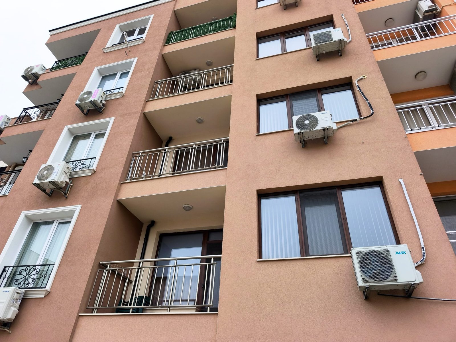 Жилой дом с кондиционерами на фасаде в urban-окружении Многоквартирный дом в Болгарии с балконами и кондиционерами, идеальный для покупки или аренды недвижимости у моря.