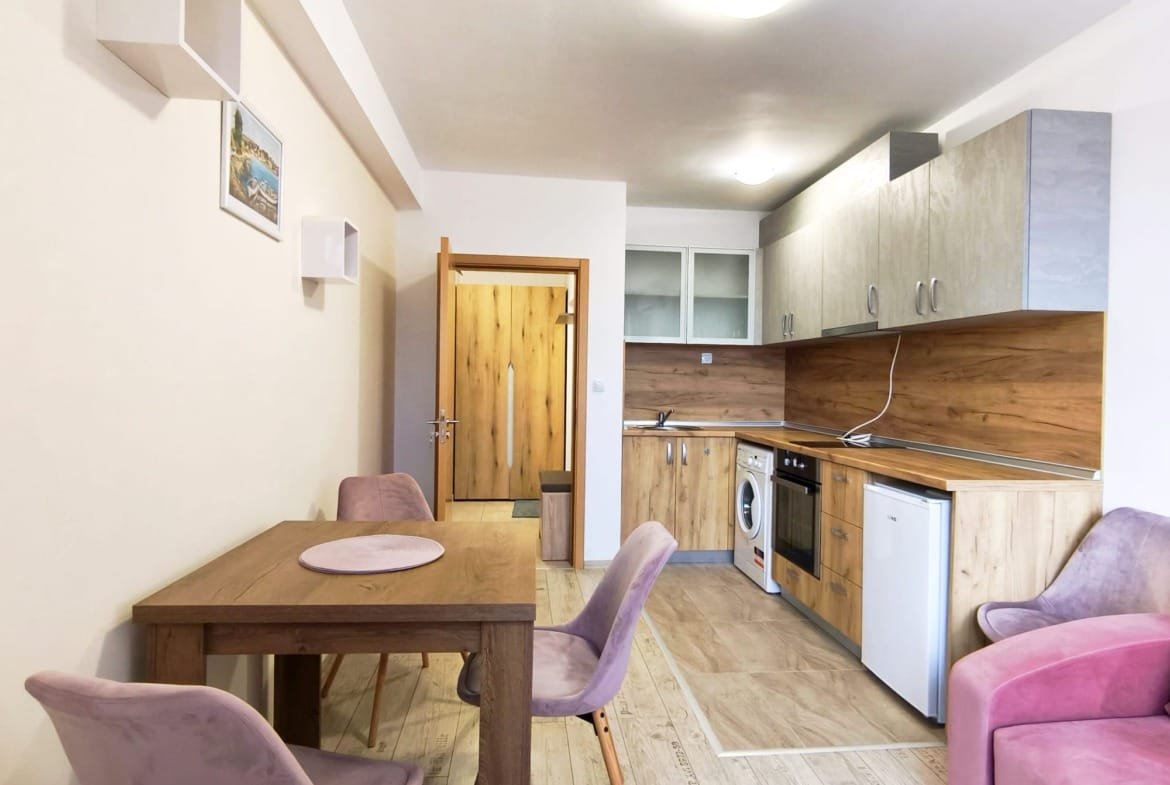 Современная квартира в Болгарии с кухней и столовой, светлые тона, деревянные элементы, уютная обстановка, подходит для жизни или аренды.
