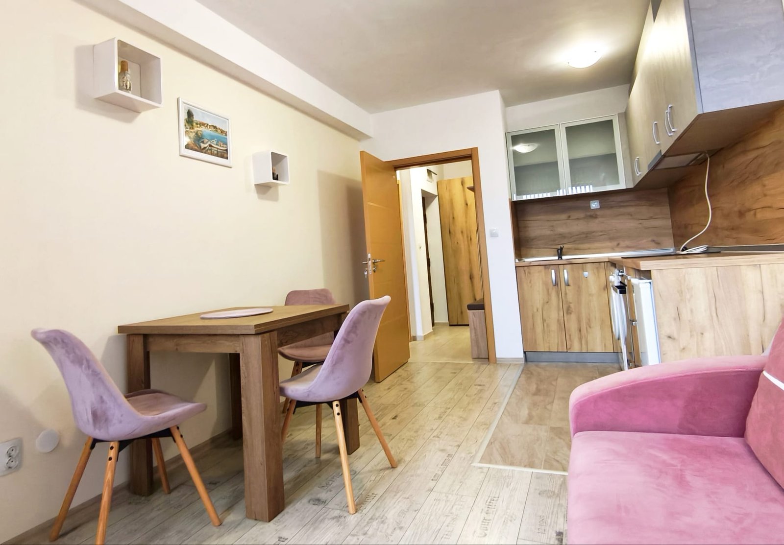 Современный интерьер квартиры с кухонной зоной и столом Современная меблированная квартира в Болгарии с уютной гостиной, кухней и обеденной зоной, идеальная для покупки или аренды.