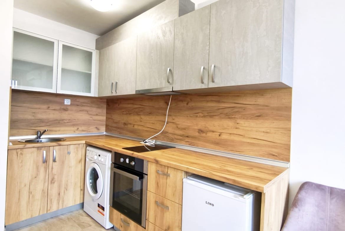 Современная кухня в квартире в Болгарии, с древесными и светлыми фасадами, оборудована техникой для комфортной жизни.