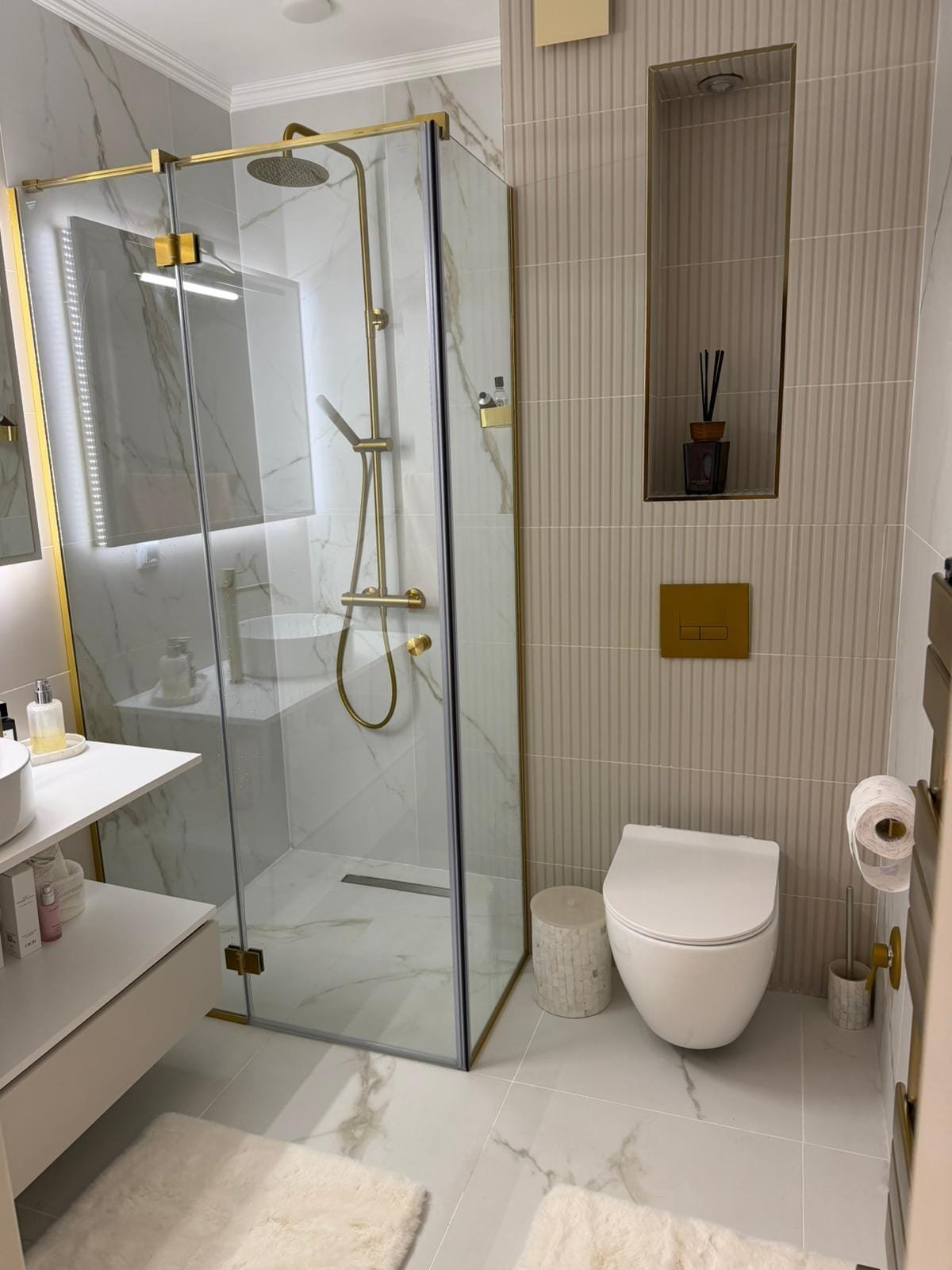 Современная ванная комната с душевой кабиной, золотыми элементами и стильным декором для успешной продажи недвижимости в Болгарии.