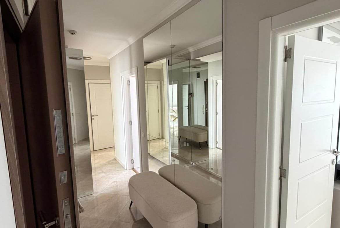 Современный коридор с зеркальными стенами, светлым интерьером и стильной мебелью для продажи недвижимости в Болгарии.