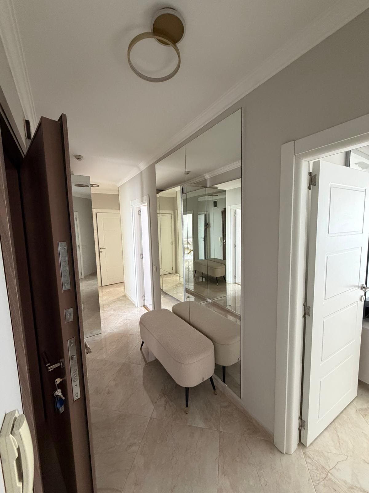 Современный коридор с зеркальными стенами, светлым интерьером и стильной мебелью для продажи недвижимости в Болгарии.