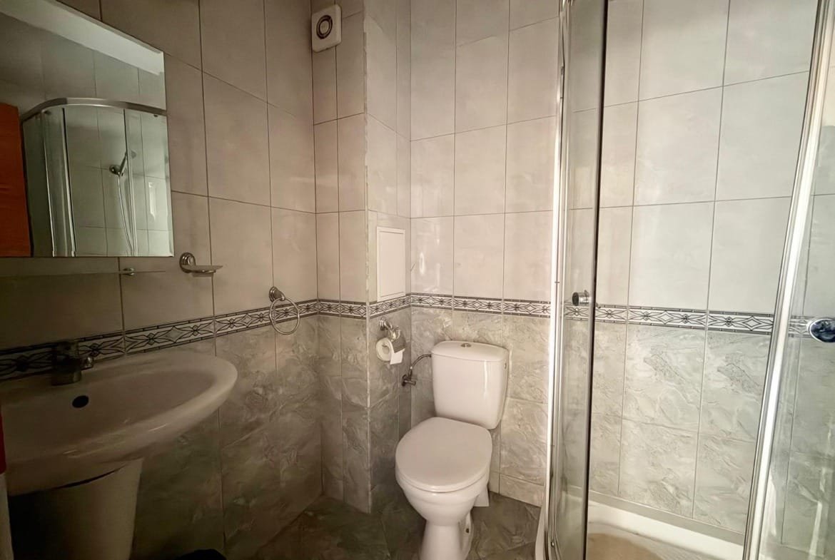 Уютная Badezimmer с белой сантехникой, душевой кабиной и современными плитками, подходит для продажи недвижимости в Болгарии.