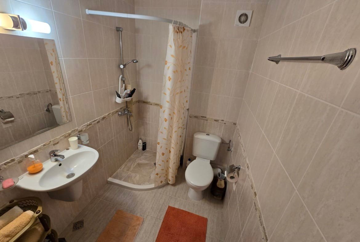 Современная ванная комната с душевой кабинкой, плиткой beige, зеркалом и аксессуарами для комфортного проживания в Болгарии.
