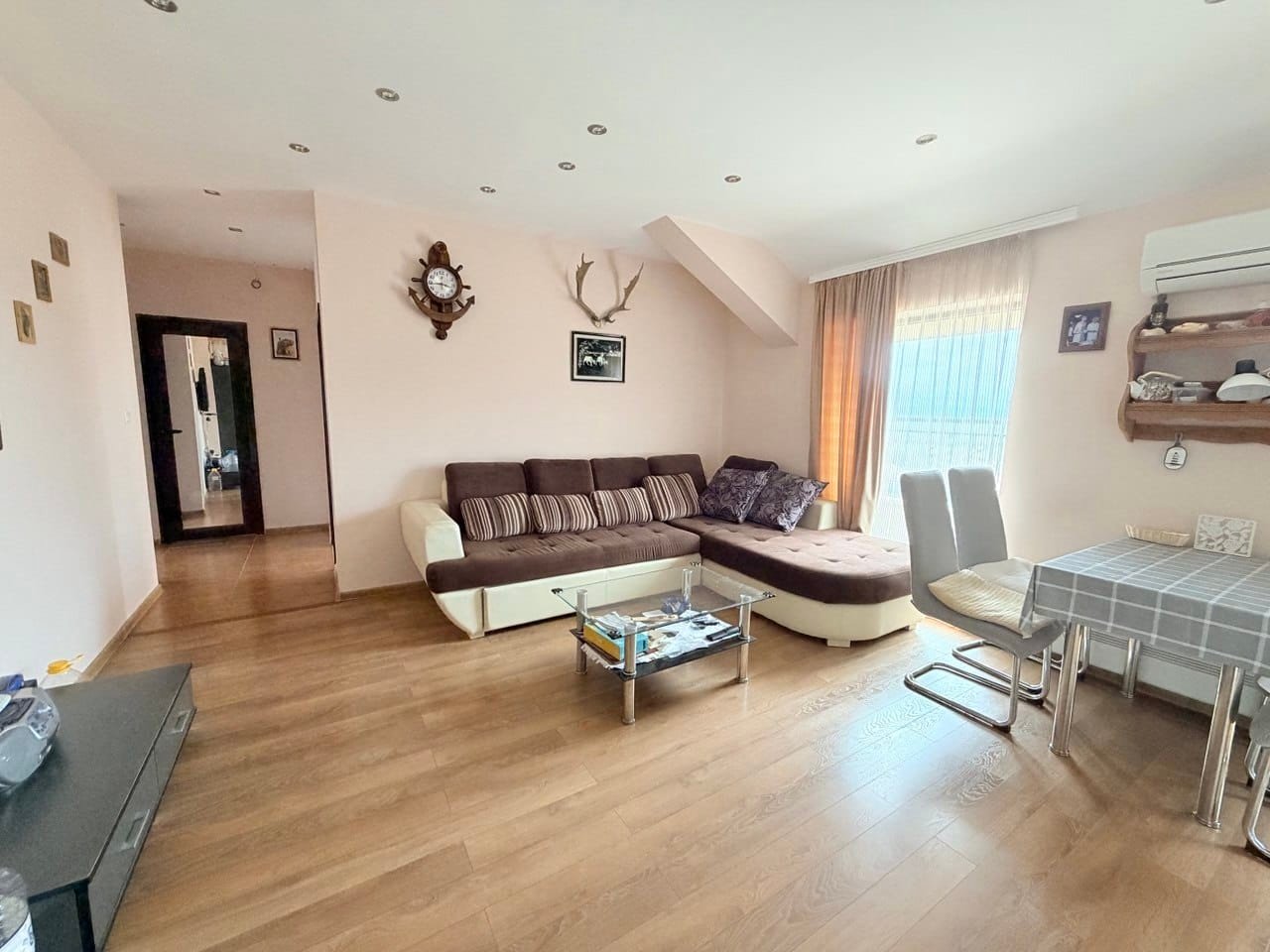 Современный интерьер квартиры с уютной гостиной и обеденной зоной Современная квартира в Болгарии с уютной гостиной, диваном, обеденным столом и светлыми стенами.