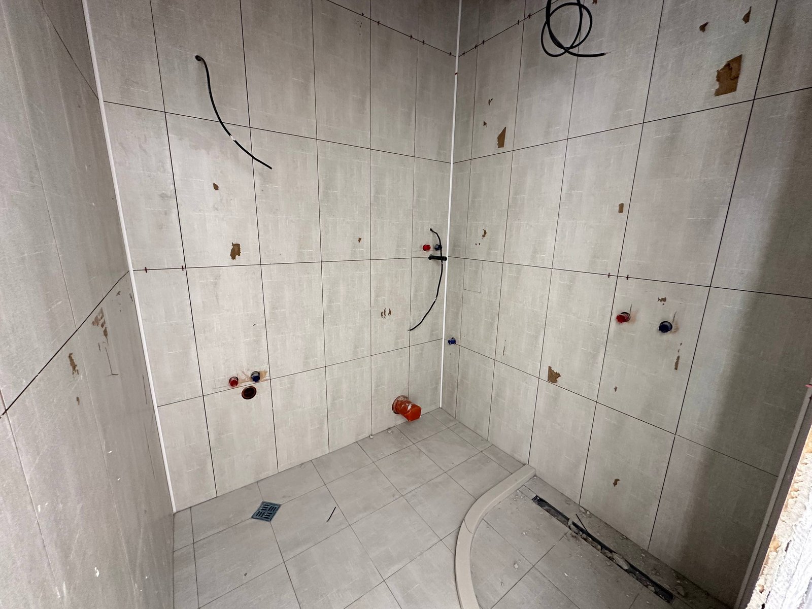 ПустаяBathroom с серыми плитками, без сантехники и отделки, подготовленная для продажи недвижимости в Болгарии.